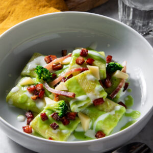 Piatto di pasta con crema di broccoli, gocce di fonduta, cubetti di Speck tostati e pezzetti di broccolo